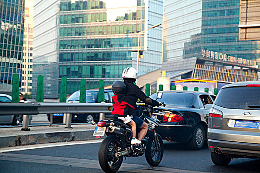车流中骑着摩托车带着孩子的父亲