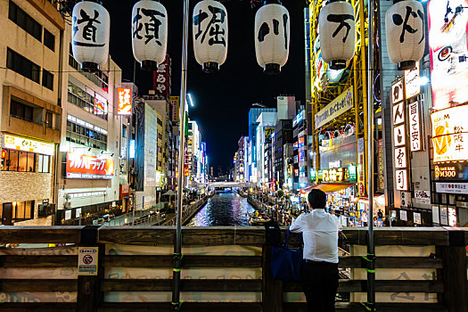 夜晚人们在日本大阪道顿堀川万灯祭的灯笼下欣赏风光