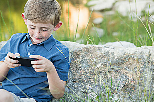 男孩,户外,坐,石头,手持,电子游戏
