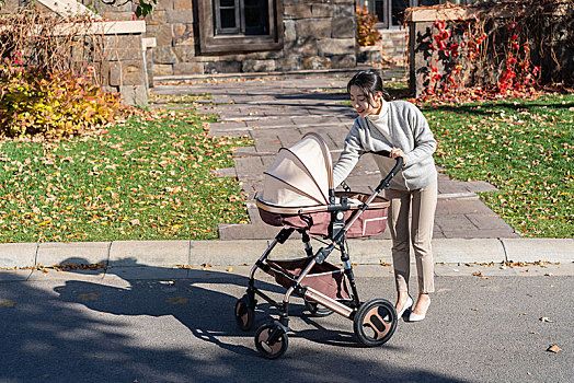 年轻母亲推着婴儿车散步