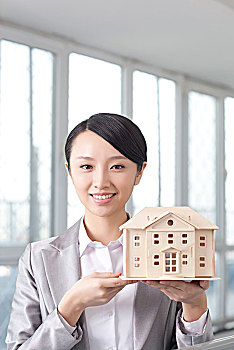东方商务女士拿着房子模型