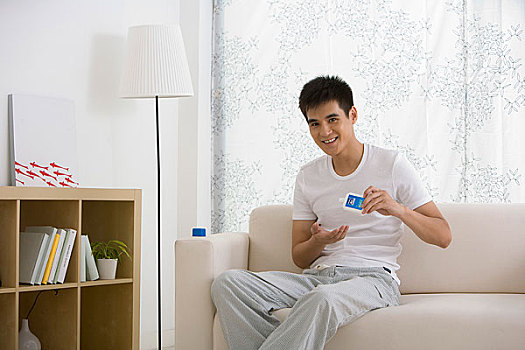 一个年轻的男人坐在家中的沙发上化妆