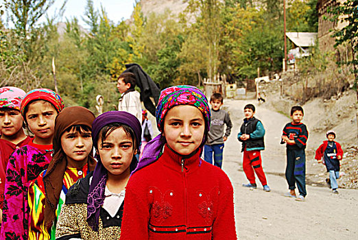 tajikistan,penjakent,children,in,traditional,dress,doing,the,dishes,with,old,schoolbus,background