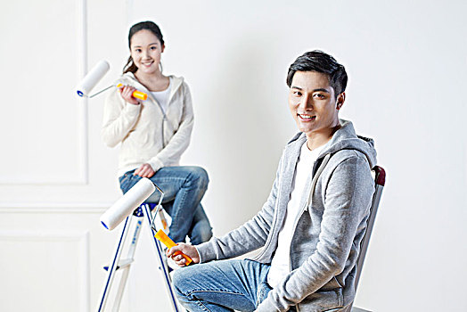 年轻情侣装修粉刷墙壁
