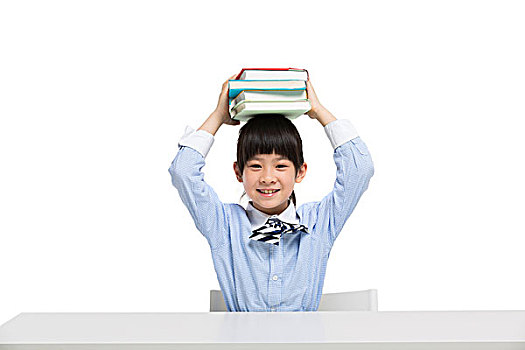 小女孩坐在课桌前头顶书本