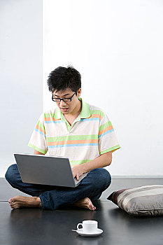 坐在地上玩电脑的男人