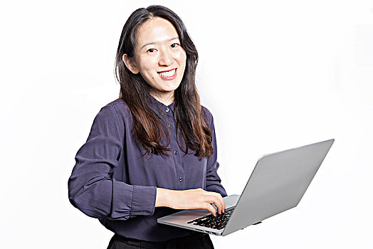 微笑的女人拿着笔记本电脑站在白色背景前面