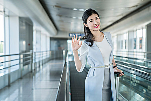 年轻商务女士在机场乘坐移动电梯