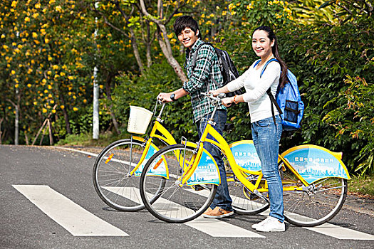 年轻大学生情侣在校园里骑车过马路