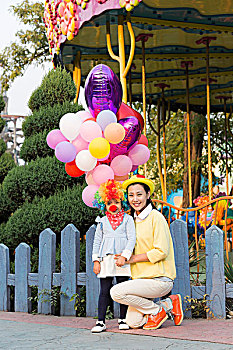 小女孩扮小丑和年轻妈妈在游乐园