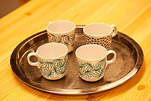 四个带花纹的陶瓷杯整齐的放在托盘中