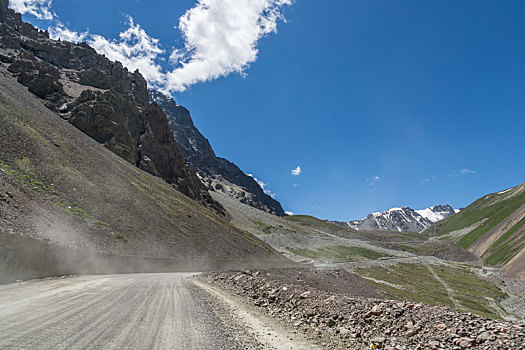 新疆蓝天白云下独库公路高原砂石路汽车背景