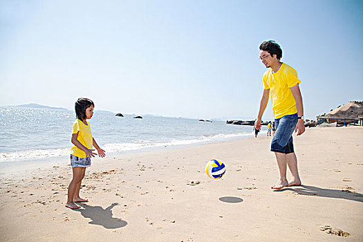 年轻父亲和女儿在沙滩上玩排球