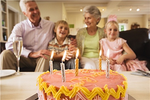 老年,夫妻,坐,孙辈,4-6岁,沙发,在家,生日蛋糕,茶几,前景