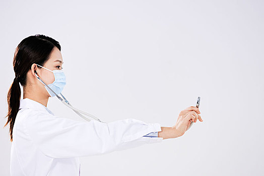 一位戴口罩的女医生使用听诊器