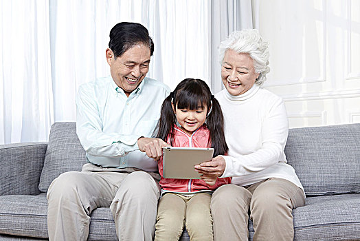 爷爷奶奶和孙女坐在沙发上玩电脑