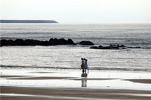 山东省日照市,雨后的海边空气清新,游客在海滩漫步乐享生活