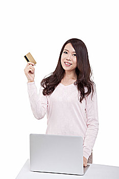 东方青年女子在电脑前拿着信用卡