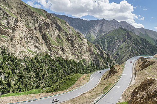 中国新疆夏季蓝天白云下g217独库公路沿途高原森林盘山道