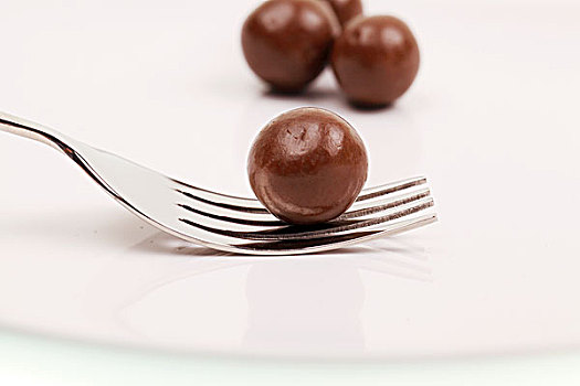 白色盘子中的四个圆形棕色巧克力豆和银色刀叉
