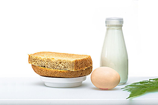 餐桌上的包鸡蛋配牛奶的营养早餐,一枝绿叶点缀