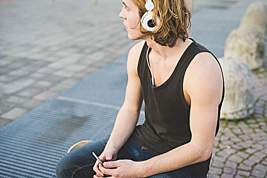 男青年,坐,人行道,听,头戴式耳机,音乐