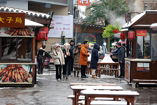 雪后的旅游小镇如诗如画,游客漫步美食街