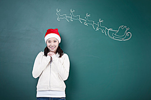 绿色黑板前许愿的女孩与圣诞图案