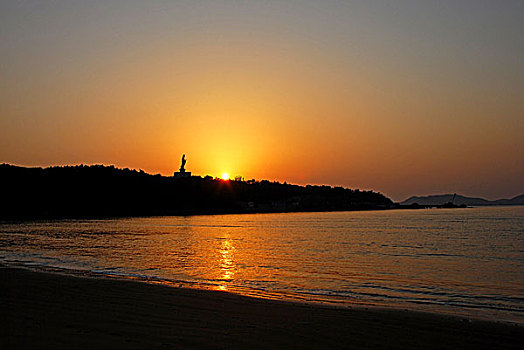 海边夕阳中的金身观音像剪影