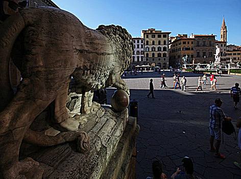 从佛罗伦萨西尼奥列广场佣兵凉廊的大理石狮子雕像旁眺望海神喷泉和科西莫一世骑马雕像