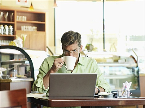 男人,坐,咖啡,桌子,使用笔记本,喝,大杯,正面,头像