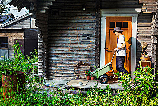 男人,戴着,帽子,站立,户外,木质,花园棚屋,推,绿色,手推车