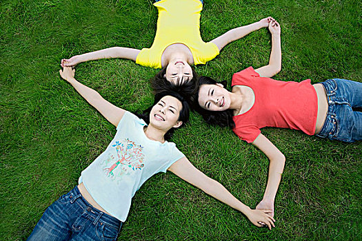 手拉手躺在草地上的三个小女孩