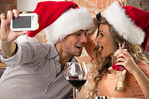 年轻,幸福伴侣,戴着,圣诞帽,看,一个,餐馆,吻,照相,手机,摄影,庆贺,圣诞节