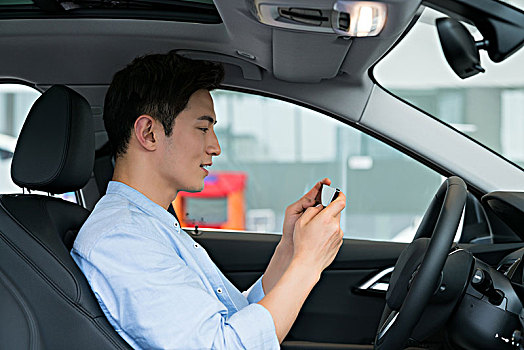 年轻商务男子在车里使用手机