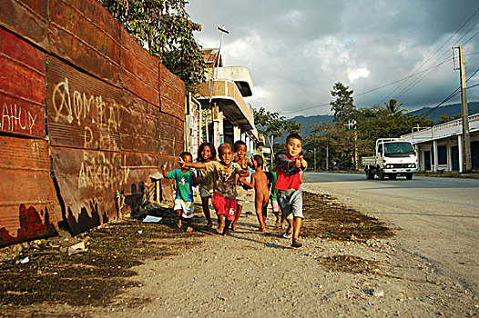east-timor,timor-leste,dili,group,of,timorese,children,with,thumbs,up,in,the,street,under,dark,clouds
